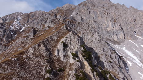 impressive rocky mountain on sunny day, aerial pullback tilt down