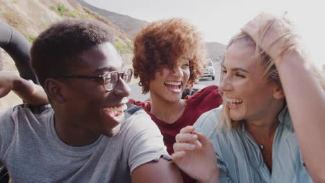 Group-Of-Young-Friends-In-Back-Of-Open-Top-Hire-Car-On-Summer-Vacation