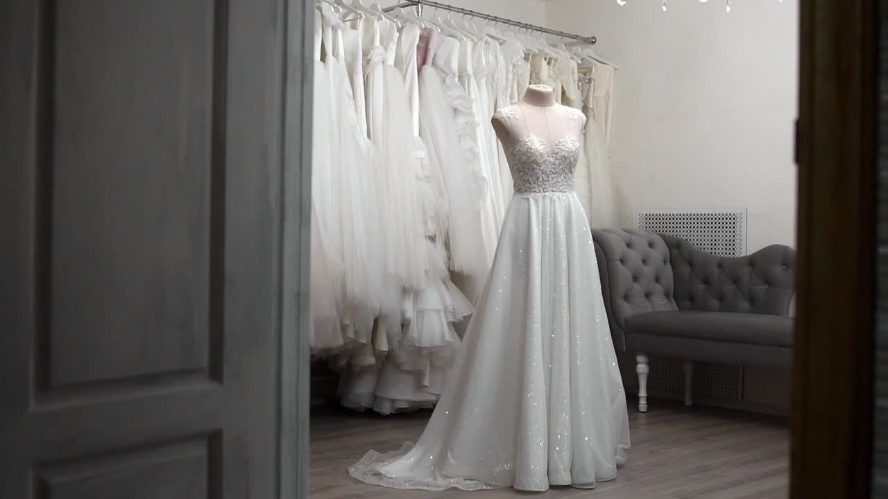bella ragazza vestito da sposa in cabina rispetto ad altri abiti. preparazione per il matrimonio. l'acquisto di un abito da sposa. la sarta ispeziona il vestito da sposa finito su misura.