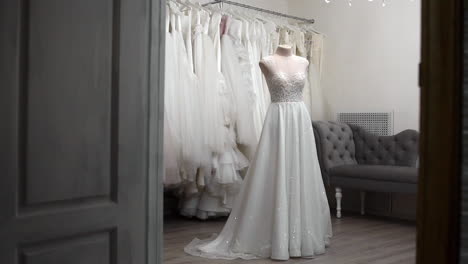 beautiful girl looking wedding dress in the cabin compared to other dresses. preparing for the wedding. buying a wedding dress. the seamstress inspects the finished custom made wedding dress.