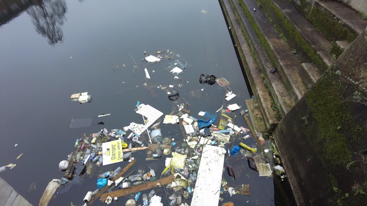 Rubbish dumped and floating in disused dock Woolwich London UK