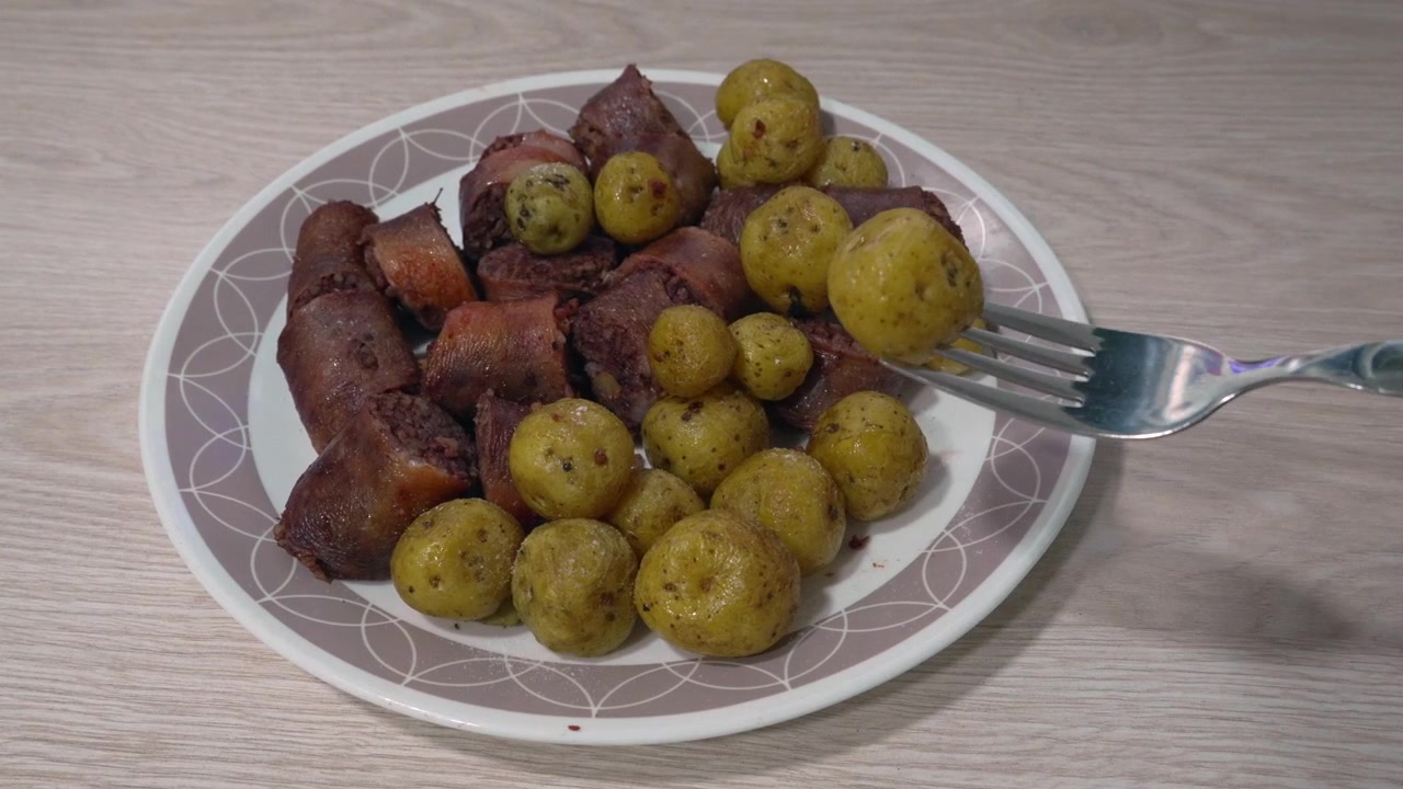 Fette di morcilla cotta e patate novelle condite servite su un piatto accanto a una ciotola di salsa aji tritata su un tavolo di legno