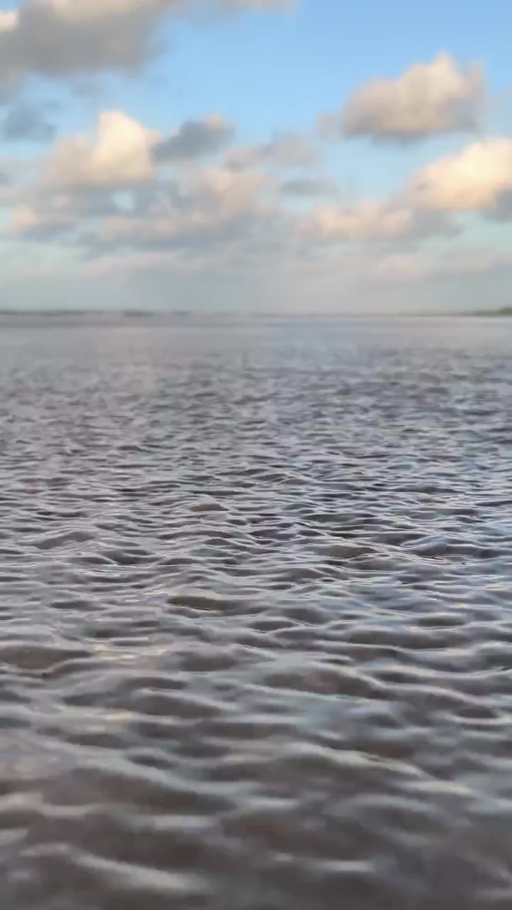 Vista en ángulo bajo de suaves ondas en un río tranquilo al atardecer