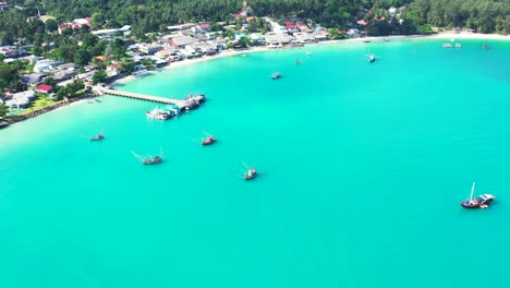 Hermosa-Laguna-Tropical-De-Color-Turquesa-Con-Barcos-Amarrados-Y-Muelle-En-La-Costa-Con-Playa-De-Arena