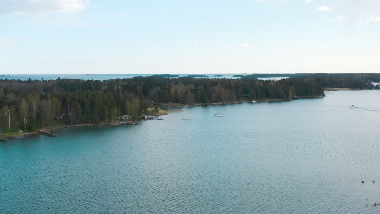 Flying towards the shoreline of tall trees a horizon filled with islands and blue water is revealed.