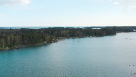 flying towards the shoreline of tall trees a horizon filled with islands and blue water is revealed.
