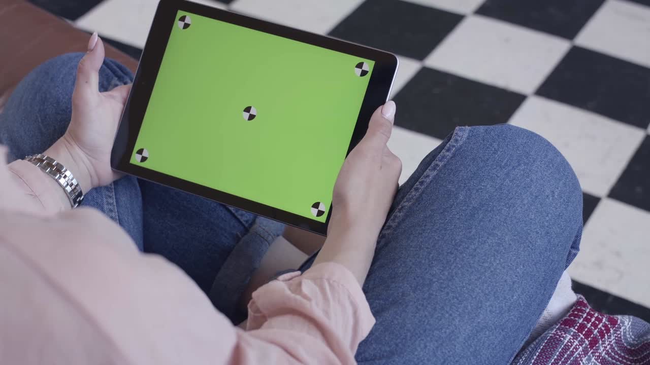 mujer sosteniendo una tableta con una pantalla verde