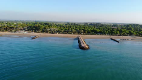 aerial over calm waters of adriatic sea moving towards the beach of coastal town caorle, italy