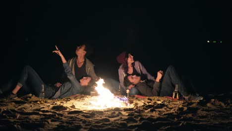 Two-cute-couples-sitting-by-the-bonfire-late-at-night-and-looking-at-the-stars