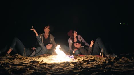 dos parejas lindas sentadas junto a la hoguera tarde en la noche y mirando las estrellas