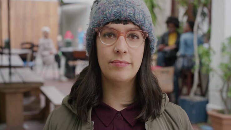 ritratto di una giovane donna hipster caucasica che guarda la telecamera seria pensiva che indossa un cappello a cappello in un ambiente urbano ristorante sullo sfondo