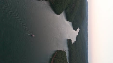 vertical aerial view of small boat on albanian river near forest hillside