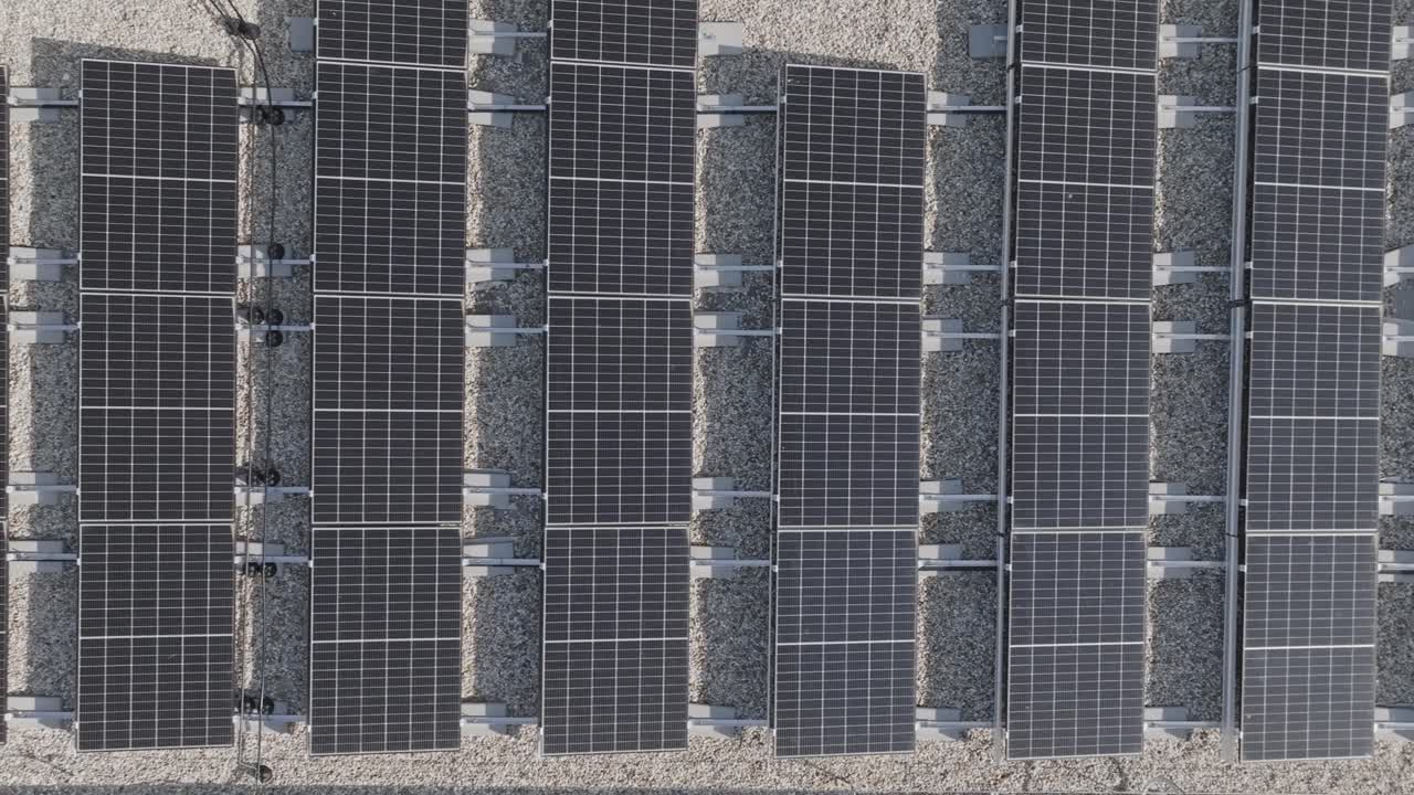 Aerial top down view of new building project with solar panels mounted on the roof using photo-voltaic cells which use sunlight as a source of energy (4K)