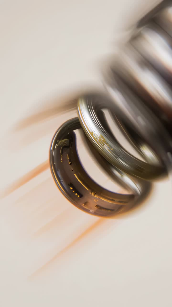 Vertical video: Flaking amber film shedding debris while metal spring forming droplets, backlit