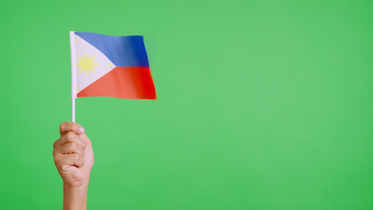 Wind waving a philippine pennant holding by a hand