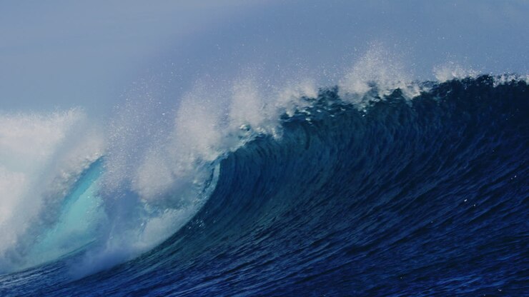 Perfecty empty blue wave barreling and crashing as ocean water sparkles in slow motion