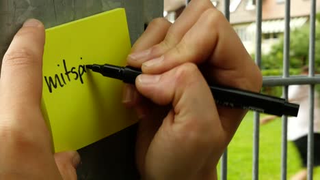 woman is writing "mitspielen"  on a post-it