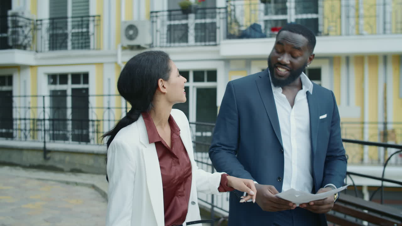 Smiling couple examining documents outdoors. Team giving high five each other