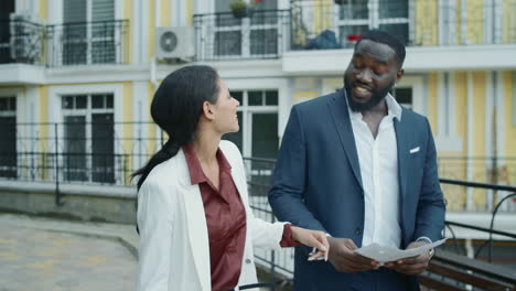 smiling couple examining documents outdoors. team giving high five each other