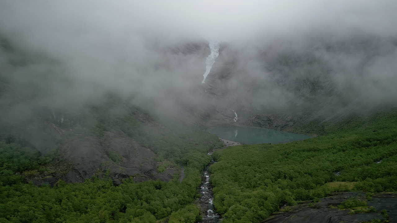 Drone shot of Briksdalsbreen in Norway. The low-hanging clouds reveal the glacier arm, which has receded in recent years due to climate change
