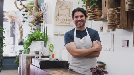 retrato de un asistente de ventas de sexo masculino sonriente de pie detrás del mostrador de ventas de la tienda de flores
