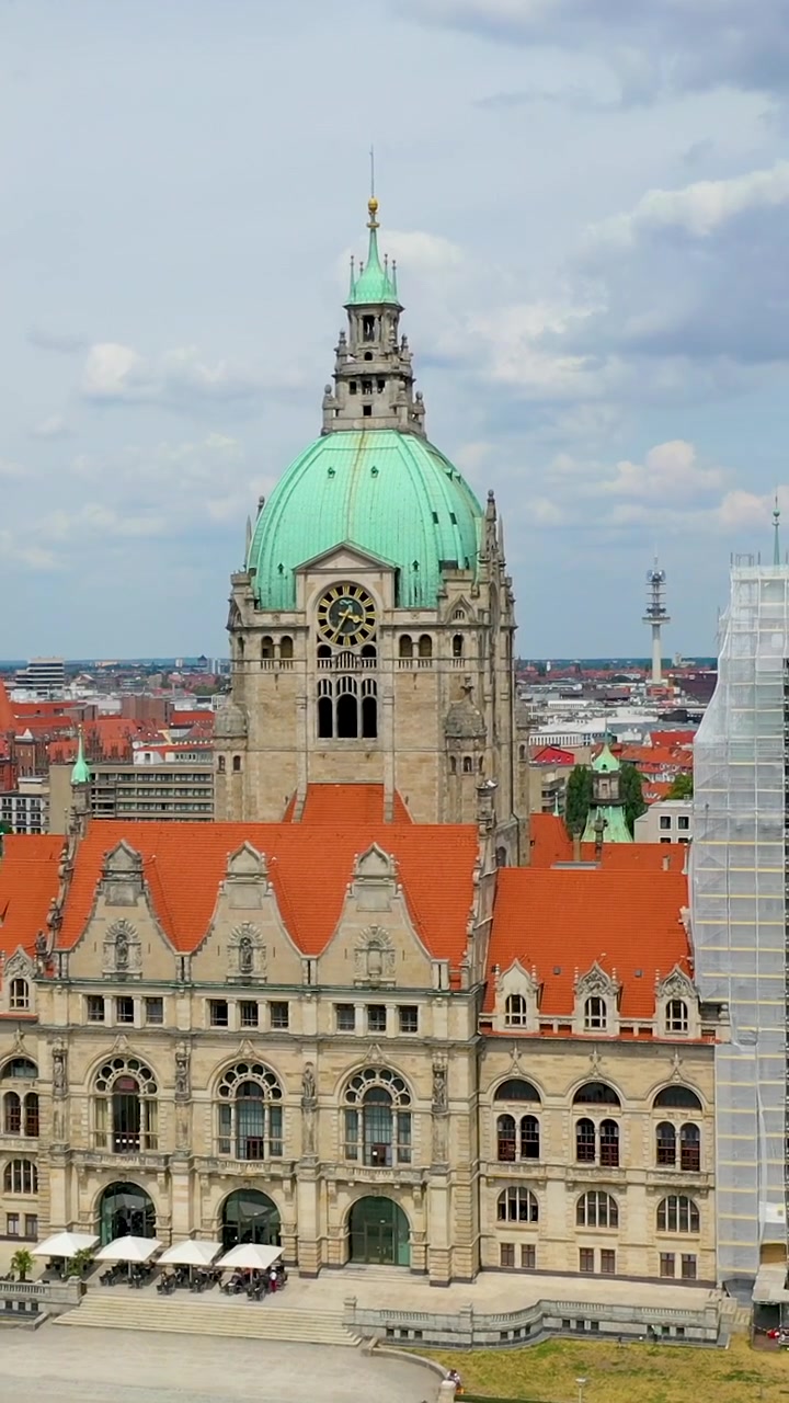 Cinematic vertical drone shot of the historic New Town Hall Neues Rathaus in Hanover, Germany, featuring its iconic green dome and ornate architecture.