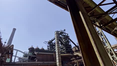 exciting-shot-through-the-rusty-old-steel-structures-of-the-landscape-park-duisburg-north-in-germany-in-good-weather,-old-pipes-and-historical-industry