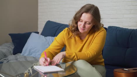 woman is writing something on sheets of paper at glass table with pen. she reads something and corrects it with pen. studying something, preparing for speech, checking contract, training, lecture