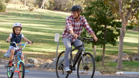 Father-and-daughter-riding-bikes-on-a-path-in-a-park