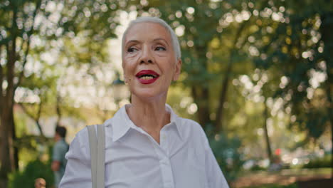 happy senior walking outdoors closeup. beautiful grey hair woman in green park