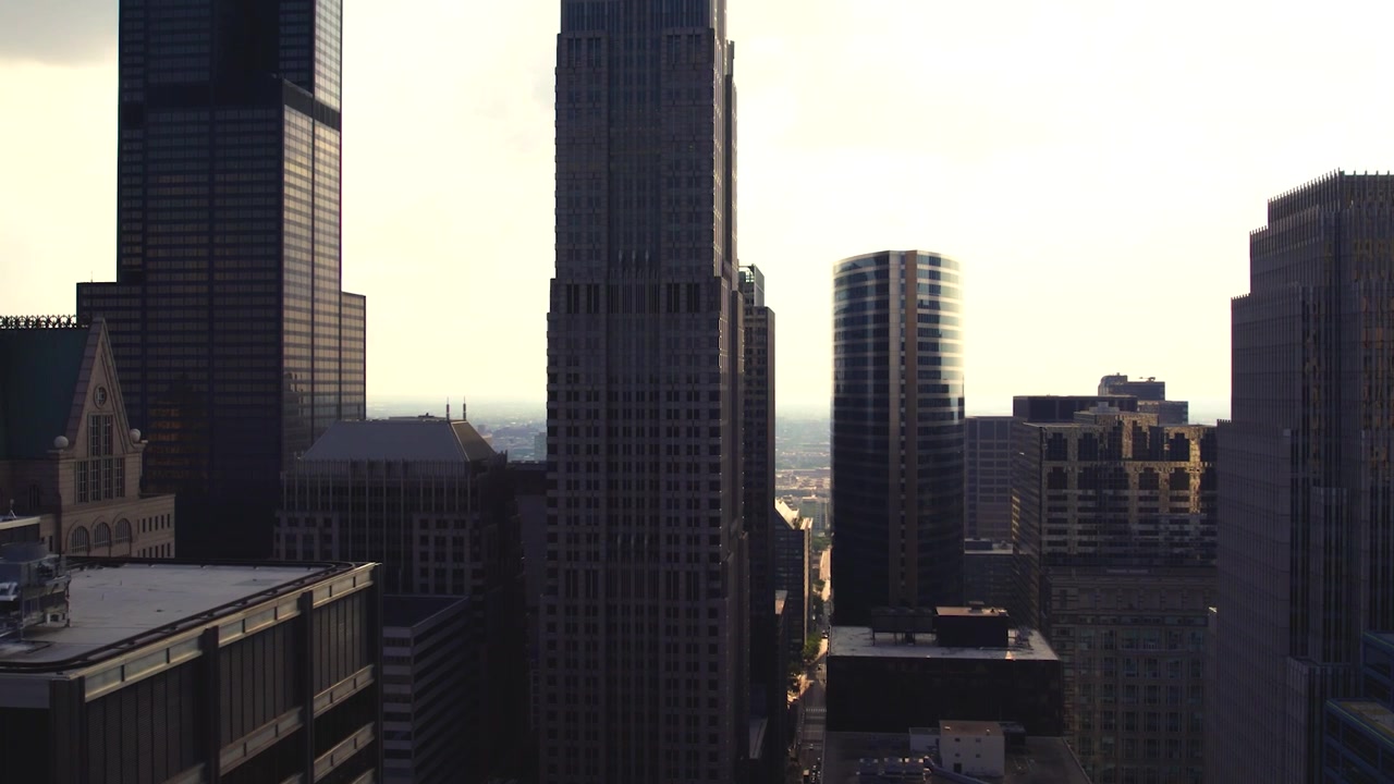 Vista aerea con drone delle torri del centro di Chicago stagliate contro la luce brillante dell'ora d'oro, con architettura fitta e strade cittadine distanti