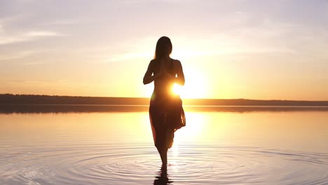 Hermosas-Imágenes-En-La-Playa-Al-Atardecer,-Una-Mujer-Haciendo-Yoga-Asana-Utthita-Hasta-Padagushthasana-Permaneciendo-En-El-Agua.-Camara-Lenta