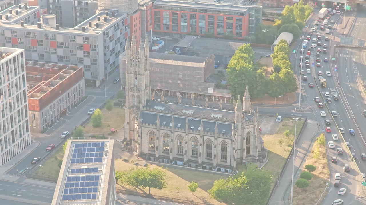 Chiesa di San Giorgio su Chester Road a Hulme, con torre in stile neogotico, pinnacoli, sagrato e strade urbane circostanti, vicino a Castlefield e alla Mancunian Way, Inghilterra, ripresa aerea di ambientazione