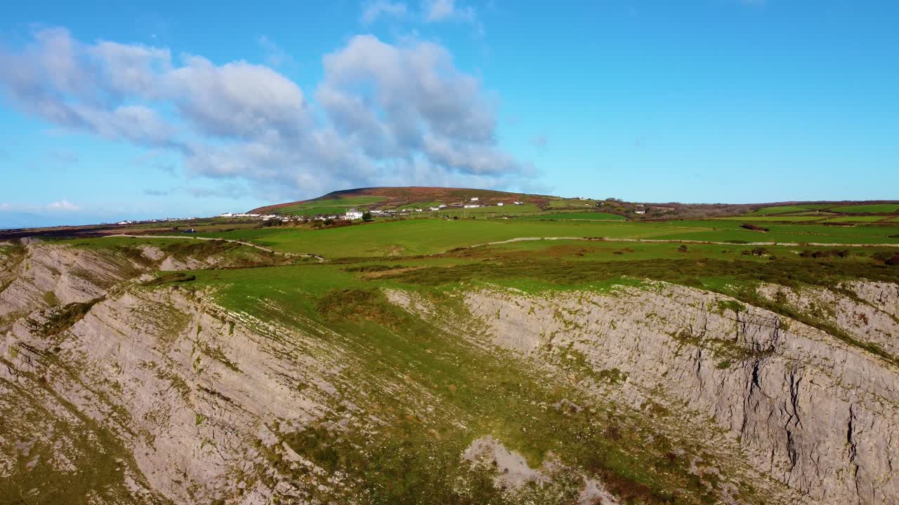 Ampia veduta aerea della costa del Galles meridionale con il villaggio rurale di Rhossili sullo sfondo, terreni agricoli e sentiero costiero. Clip di viaggio naturalistico con drone. Splendida costa della penisola gallese di Gower.