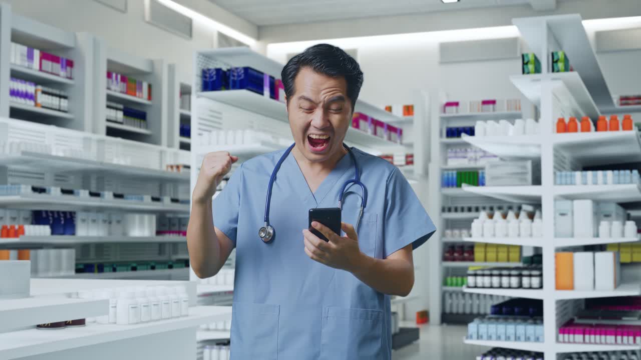 스마트폰을 사용하고 약국에 서서 성공을 축하하는 스테토스코프를 가진 아시아 남성 의사