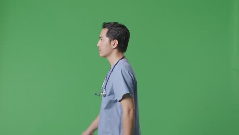 side view of asian male doctor with stethoscope walking on green screen background in the hospital