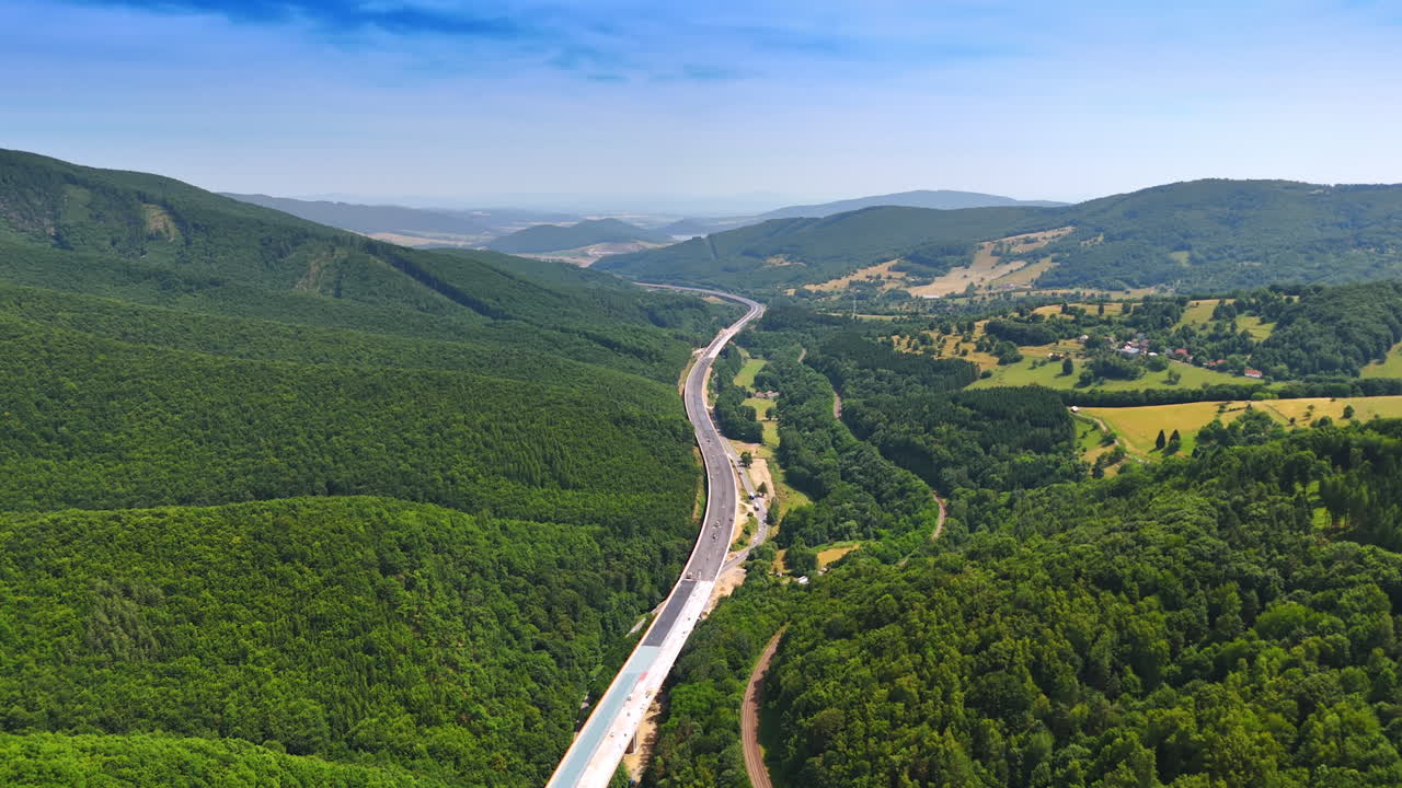 Mountain road view. A stunning aerial view captures a winding road through lush green mountains under a clear blue sky during daytime