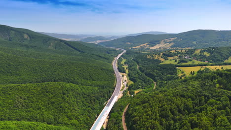 Mountain road view. A stunning aerial view captures a winding road through lush green mountains under a clear blue sky during daytime