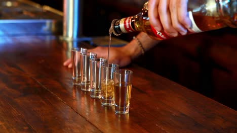 barman giet tequila in een shotglas bij de bar.