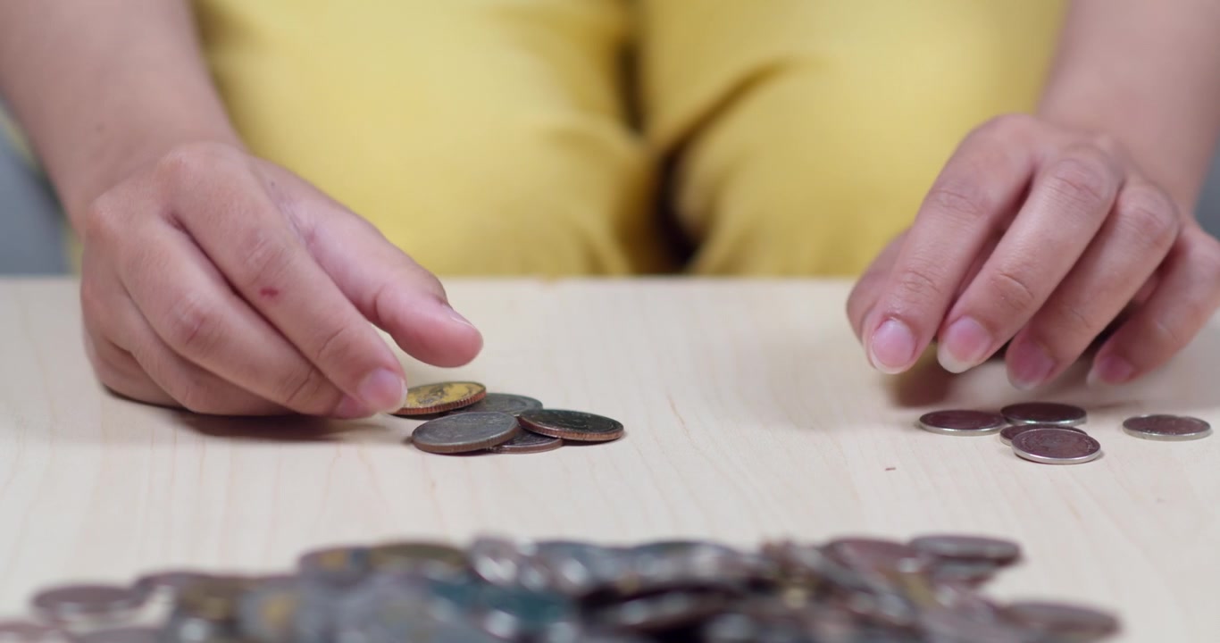 Una vista de cerca de manos clasificando y contando monedas, mostrando habilidades de educación financiera