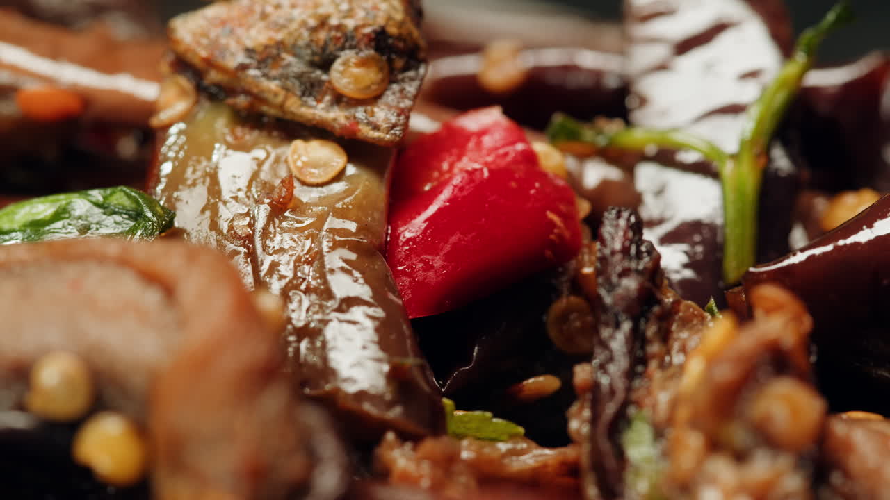 Close-up of fermented eggplants with red sweet pepper and mustard on plate. Preservation of vegetables in glass jars. Fermentation preserved aubergine with hot chilli peppers and greens.
