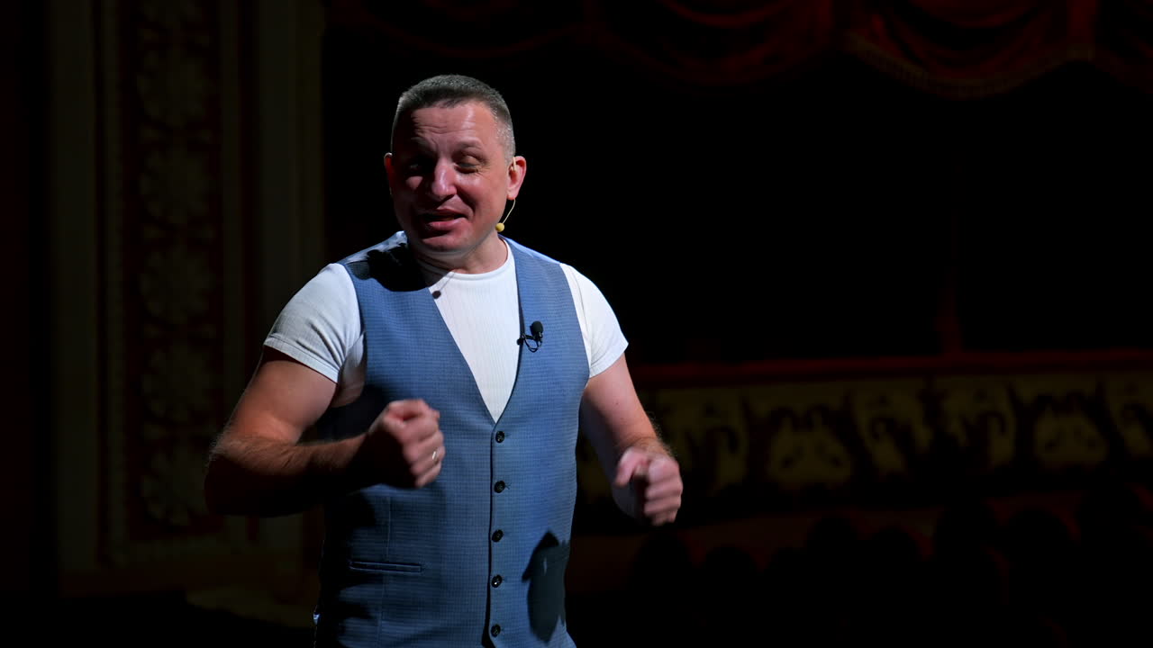 Man in suit speaking jokes in micropphone standing on stage. Funny performance. Comedian in good humor speaks to the audience.