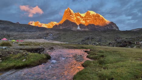 nature background: golden hour mountain peak with alpine meadow stream