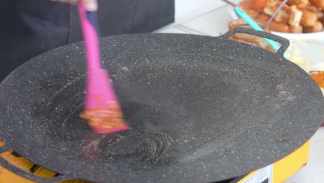 woman using spatula putting butter and seasoning on frying pan before cooking