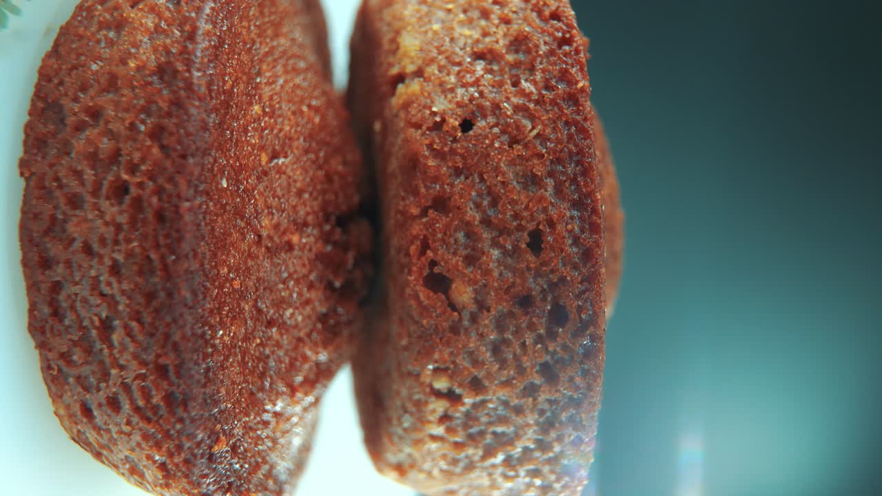 A vertical macro close up shot of tasty cupcakes, on a 360 rotating stand, white plate, studio lighting, slow motion, smooth movement, 4K video