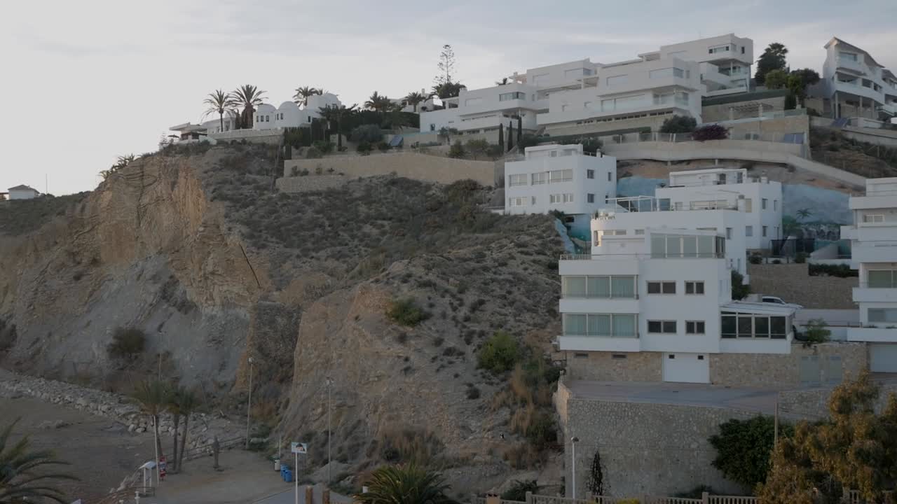 White modern homes above rocky coastline at punta del bon nou, alicante, aerial view