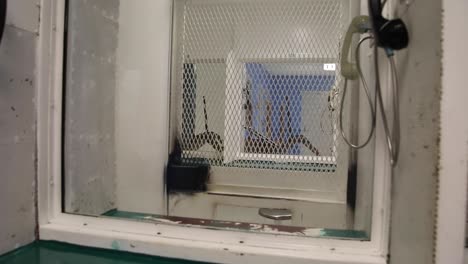 Prison-phone-booth-in-jail-where-prisoners-can-speak-to-family-members-during-visitation-through-glass-window