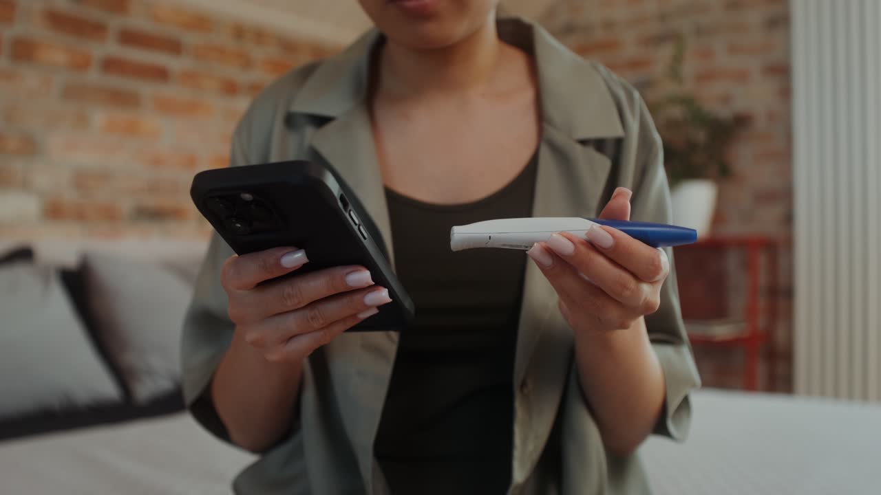 mujer comprobando los resultados de la prueba de embarazo por teléfono