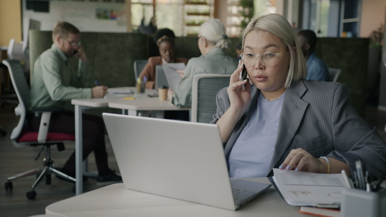 Forretningskvinne i telefonsamtale på moderne kontor