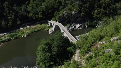 approaching drone shot with a view from above of the devil's bridge and arda river located near the town of ardino at the foot of the rhodope mountains in bulgaria